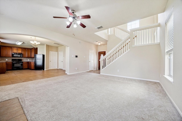 unfurnished living room featuring arched walkways, light colored carpet, visible vents, baseboards, and stairs