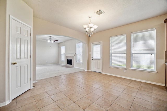 unfurnished living room featuring plenty of natural light, light tile patterned flooring, a tile fireplace, and visible vents