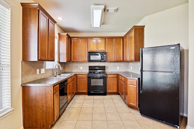 kitchen featuring light tile patterned floors, black appliances, brown cabinetry, and a sink