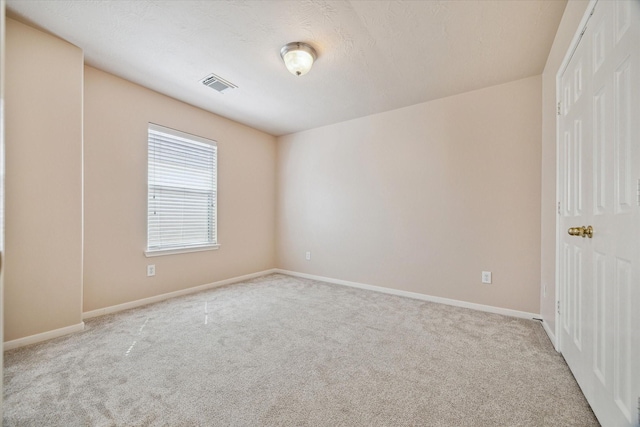 carpeted spare room featuring visible vents and baseboards