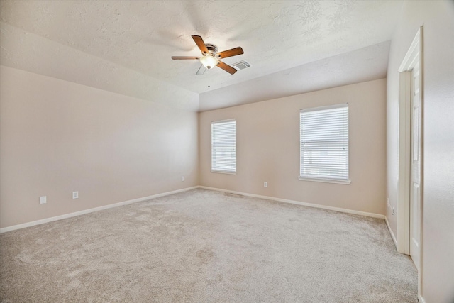 unfurnished room with visible vents, baseboards, light colored carpet, ceiling fan, and a textured ceiling