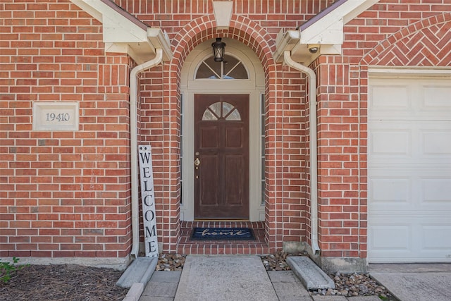 doorway to property with brick siding and an attached garage