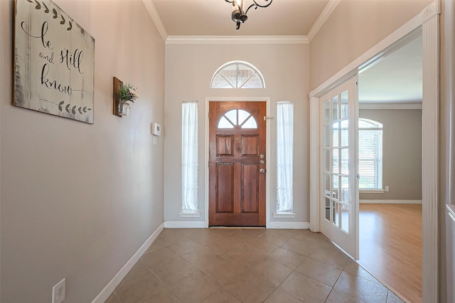 foyer featuring baseboards, light tile patterned floors, and crown molding