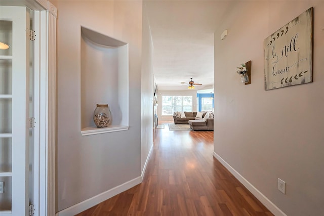 hall with baseboards and wood finished floors