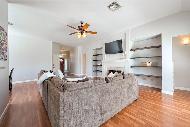 living area featuring baseboards, a fireplace, visible vents, and wood finished floors