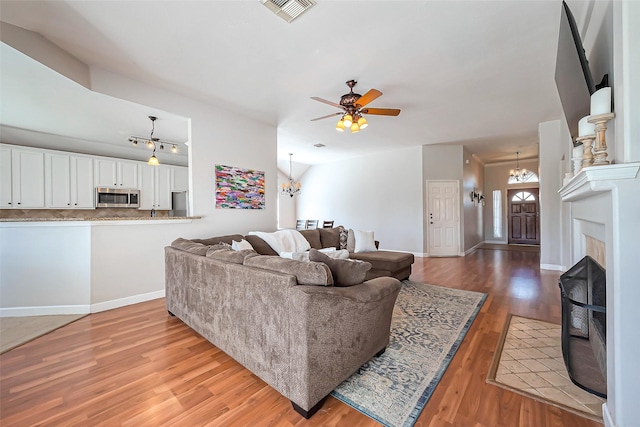 living room with baseboards, visible vents, wood finished floors, and ceiling fan with notable chandelier