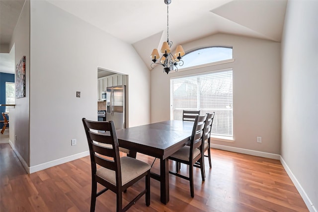 dining space featuring light wood-style floors, baseboards, a chandelier, and vaulted ceiling