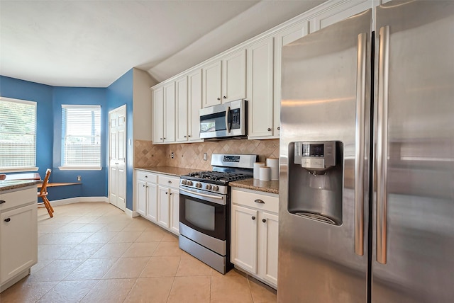 kitchen featuring light tile patterned floors, stainless steel appliances, backsplash, and white cabinets