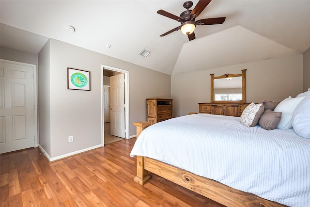 bedroom with lofted ceiling, visible vents, light wood-style floors, ceiling fan, and baseboards