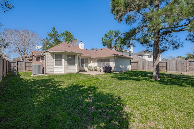 rear view of property featuring a sunroom, a fenced backyard, a chimney, a yard, and a patio area