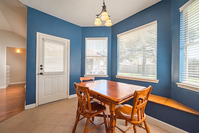 dining area featuring light tile patterned floors, a chandelier, and baseboards