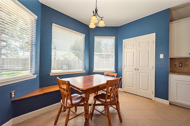 dining room featuring light tile patterned floors, baseboards, and an inviting chandelier