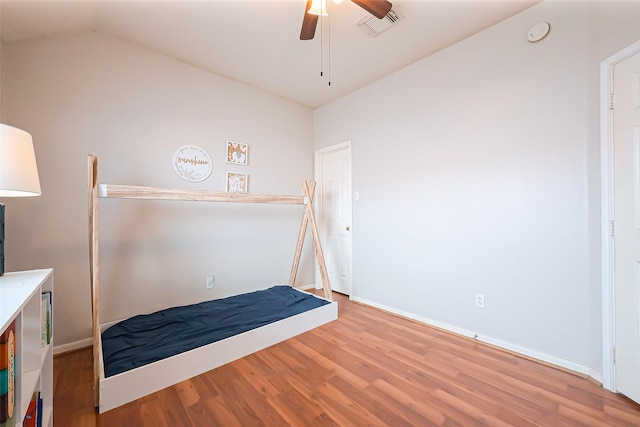 unfurnished bedroom with baseboards, visible vents, a ceiling fan, lofted ceiling, and wood finished floors