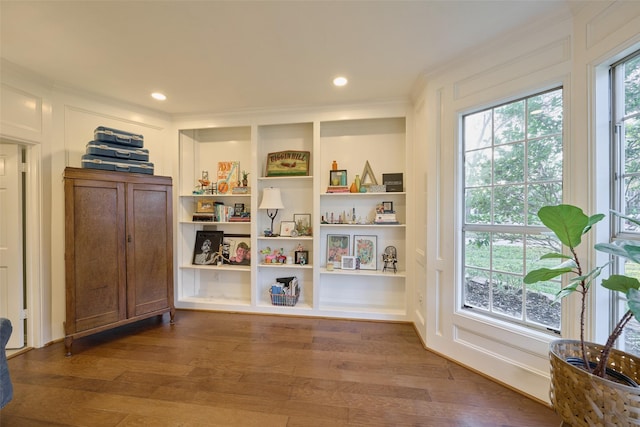 living area with built in shelves, recessed lighting, crown molding, and wood finished floors