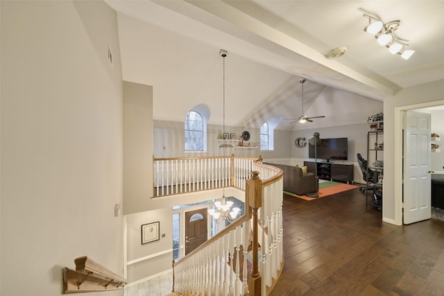 interior space with baseboards, wood finished floors, high vaulted ceiling, beam ceiling, and ceiling fan with notable chandelier