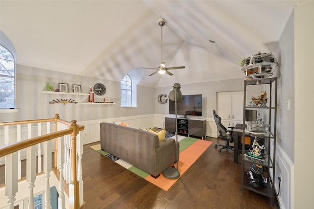 living room with a wainscoted wall, dark wood finished floors, lofted ceiling, visible vents, and a ceiling fan