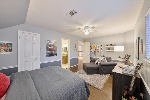 bedroom featuring ceiling fan, connected bathroom, wood finished floors, visible vents, and vaulted ceiling