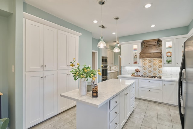 kitchen featuring visible vents, white cabinets, a kitchen island, stainless steel appliances, and premium range hood