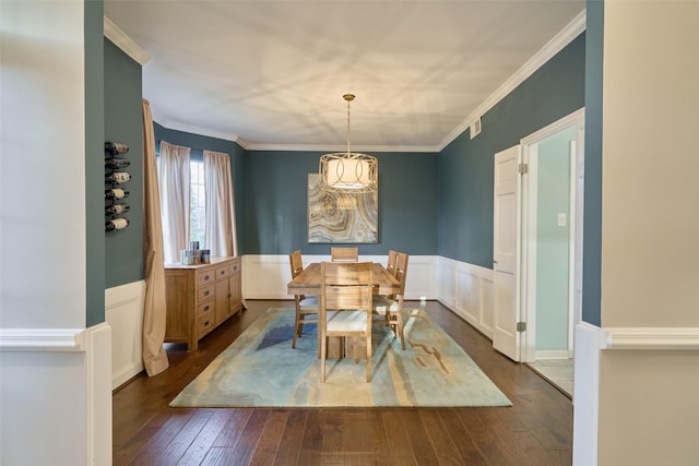 dining area featuring dark wood-style flooring, a wainscoted wall, and crown molding