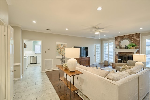 living area featuring a wealth of natural light, visible vents, and crown molding