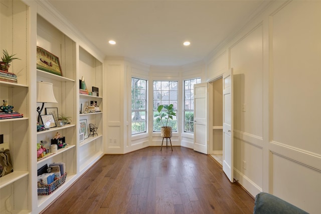 doorway with ornamental molding, dark wood-type flooring, built in shelves, a decorative wall, and recessed lighting