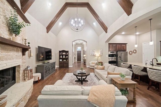 142 Monterrey Bnd, Montgomery, TX 77316 - living room with high vaulted ceiling, arched walkways, a stone fireplace, dark wood-type flooring, and a notable chandelier
