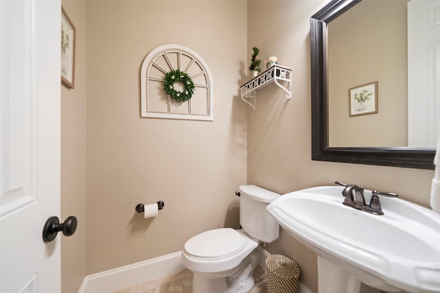 bathroom with toilet, baseboards, and a sink