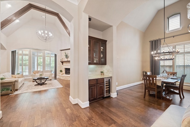 interior space with dark wood-type flooring, wine cooler, a notable chandelier, and high vaulted ceiling