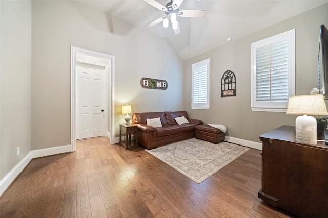 living area with baseboards, lofted ceiling, wood finished floors, and a ceiling fan