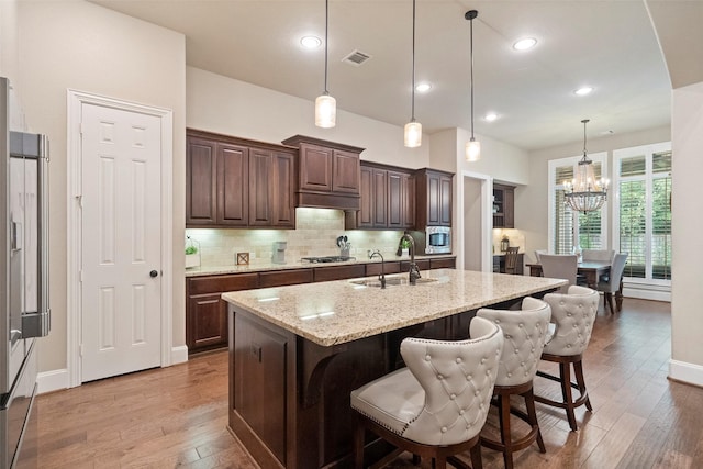 kitchen with tasteful backsplash, visible vents, built in appliances, light wood-style flooring, and a sink