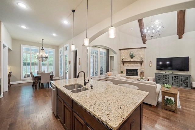 kitchen featuring a sink, a fireplace, a chandelier, dark wood-style flooring, and vaulted ceiling