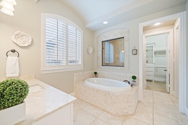 bathroom featuring a walk in closet, tile patterned floors, a garden tub, and vanity