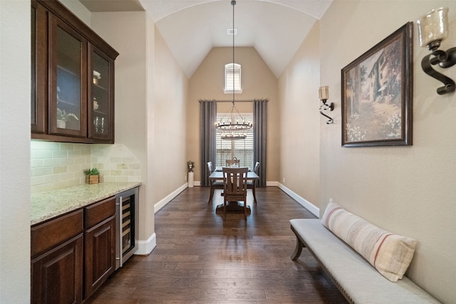 hallway with beverage cooler, dark wood finished floors, baseboards, and lofted ceiling