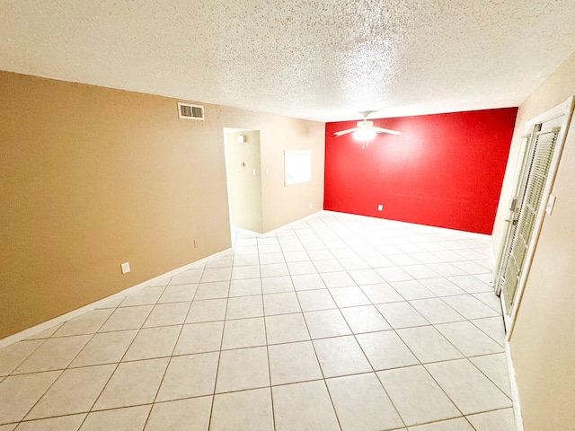 spare room with an accent wall, a textured ceiling, visible vents, and a ceiling fan