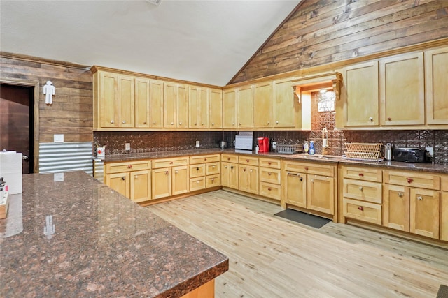 kitchen with decorative backsplash, lofted ceiling, light wood-type flooring, light brown cabinets, and a sink