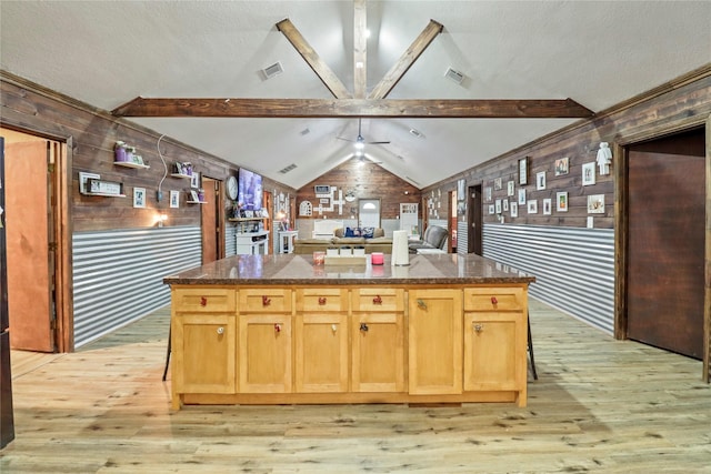 kitchen featuring lofted ceiling with beams, dark stone counters, visible vents, and elevator