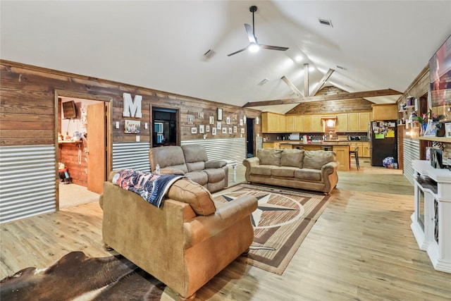 living room featuring light wood finished floors, visible vents, vaulted ceiling, and a ceiling fan