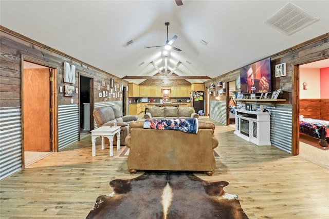 living room with wooden walls, visible vents, ceiling fan, light wood-style flooring, and vaulted ceiling