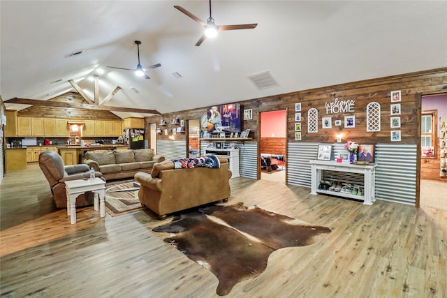 living room with wood walls, light wood-style flooring, and a ceiling fan