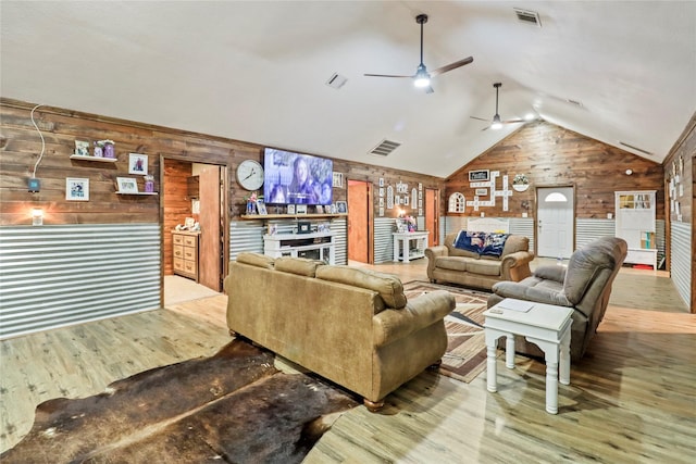 living area with lofted ceiling, wood walls, wood finished floors, and visible vents