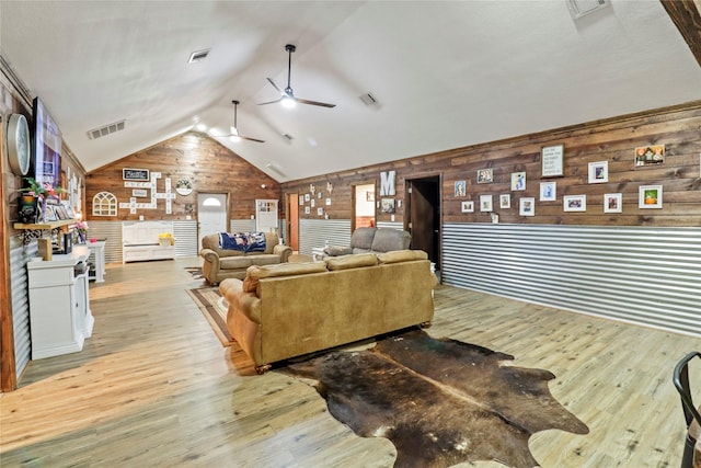 living room featuring vaulted ceiling, wood finished floors, and visible vents