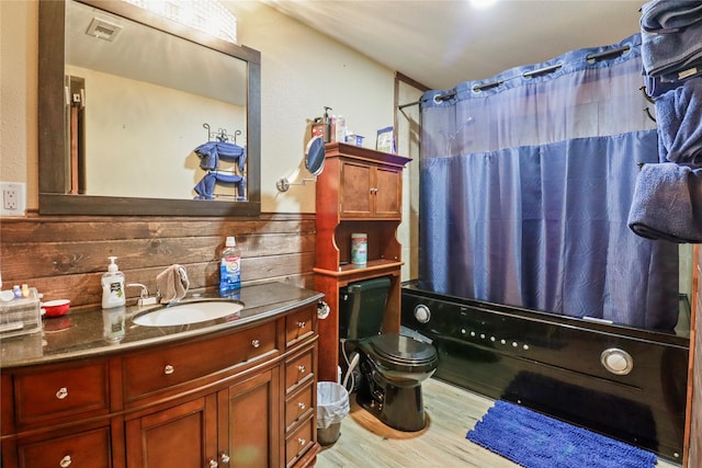 full bathroom with visible vents, toilet, shower / bath combo with shower curtain, vanity, and wood finished floors