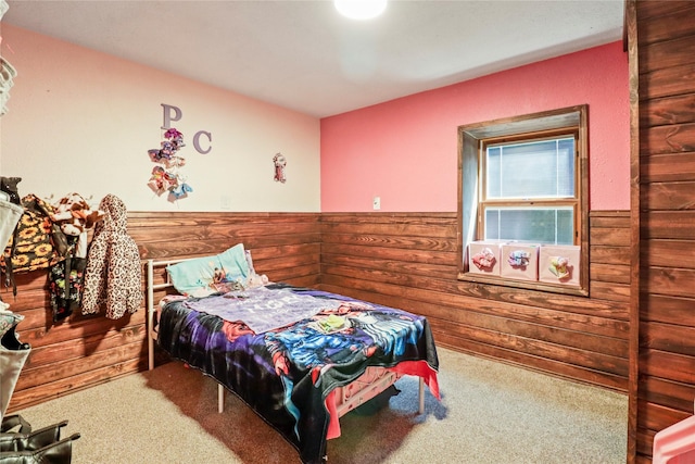 carpeted bedroom featuring wooden walls and wainscoting