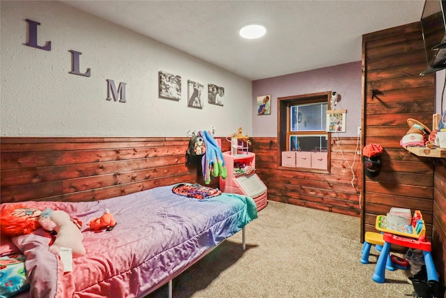 bedroom featuring carpet floors, a wainscoted wall, and wood walls