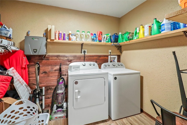 laundry room featuring a textured wall, laundry area, washer and clothes dryer, and wood finished floors