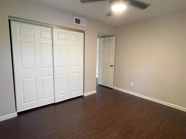 unfurnished bedroom with a closet, visible vents, dark wood-type flooring, ceiling fan, and baseboards