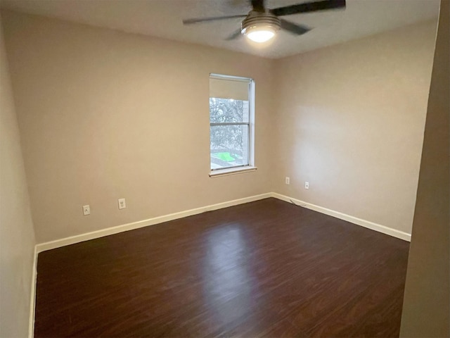 unfurnished room with a ceiling fan, baseboards, and dark wood-type flooring