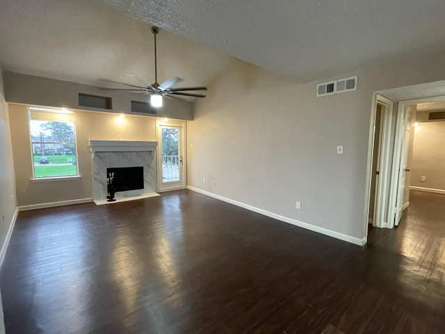 unfurnished living room with baseboards, visible vents, a premium fireplace, dark wood-style flooring, and vaulted ceiling