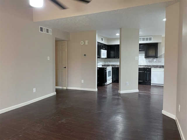 unfurnished living room with dark wood-type flooring, visible vents, and baseboards