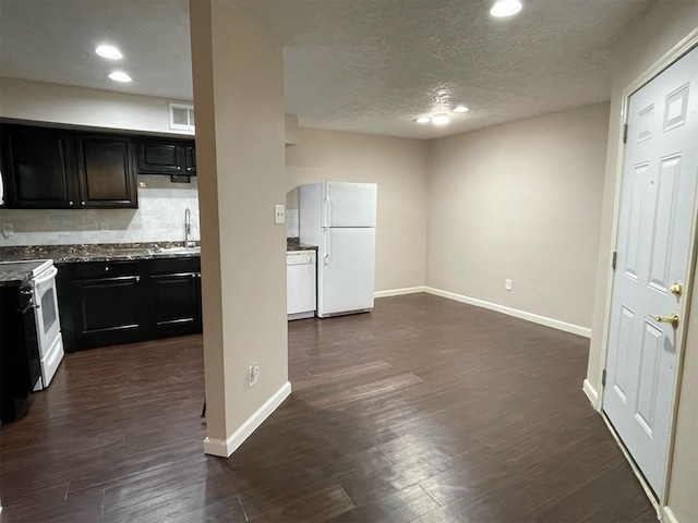 kitchen featuring dark wood finished floors, visible vents, decorative backsplash, a sink, and white appliances